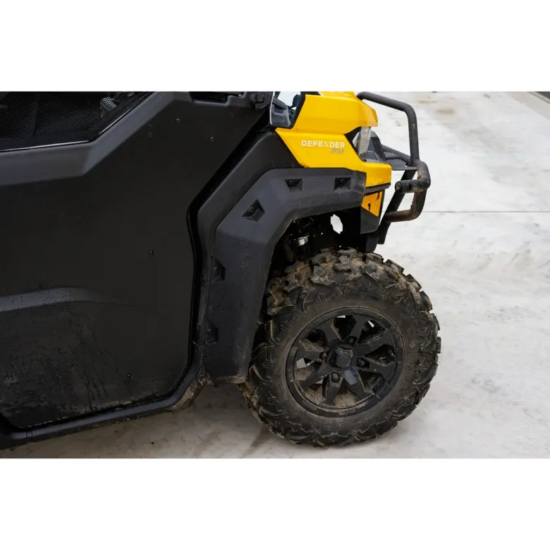 Close-up of installed Can-Am Defender fender flare on yellow model with muddy tires